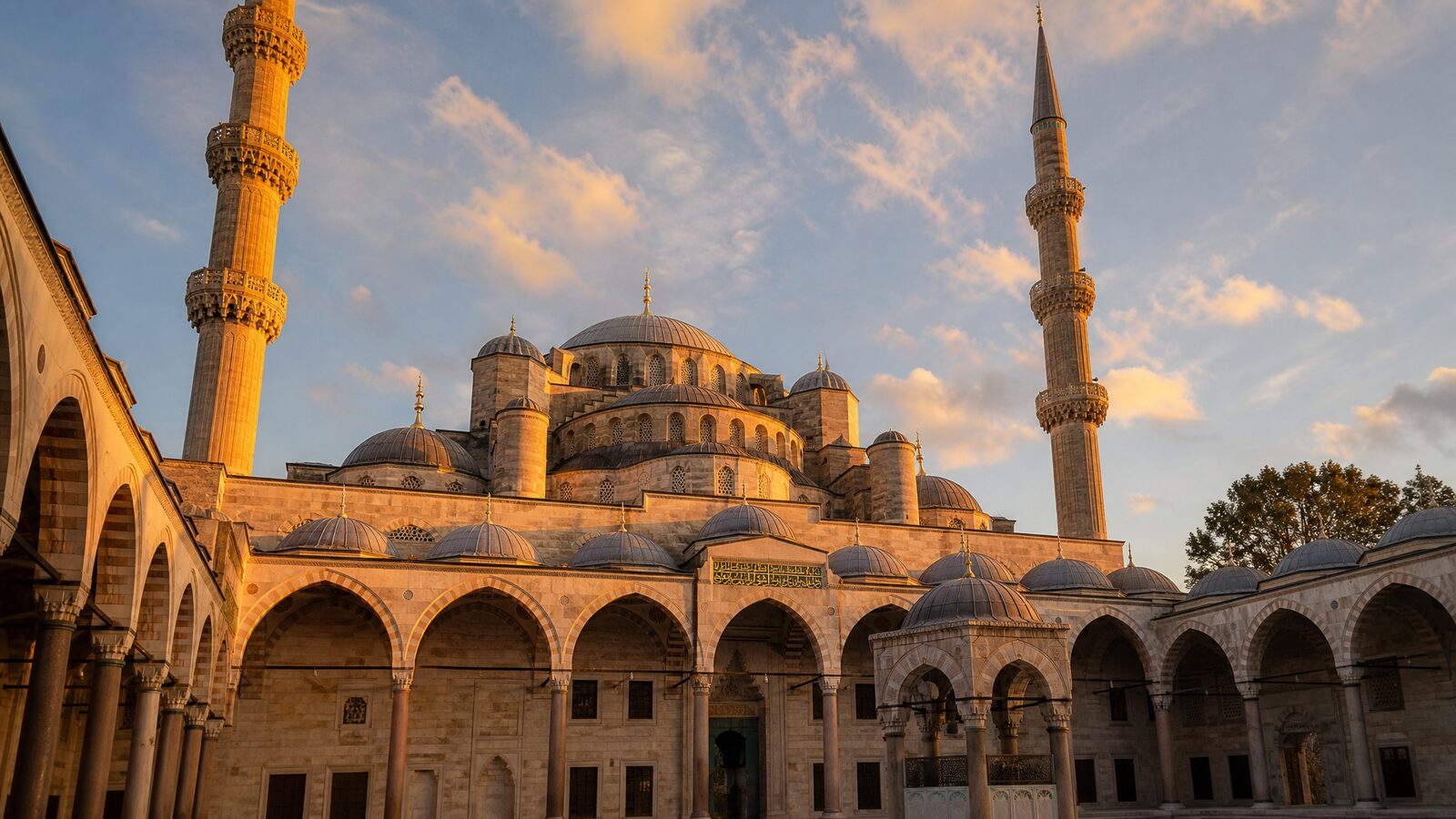 A beautiful Ottoman mosque at sunset with travellers nearby in Türkiye